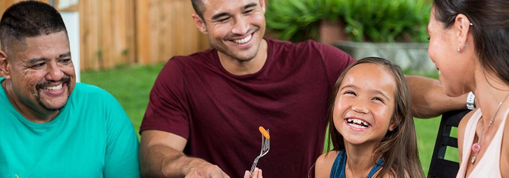 A healthy family with good teeth and healthy smiles are enjoying dinner in their yard.