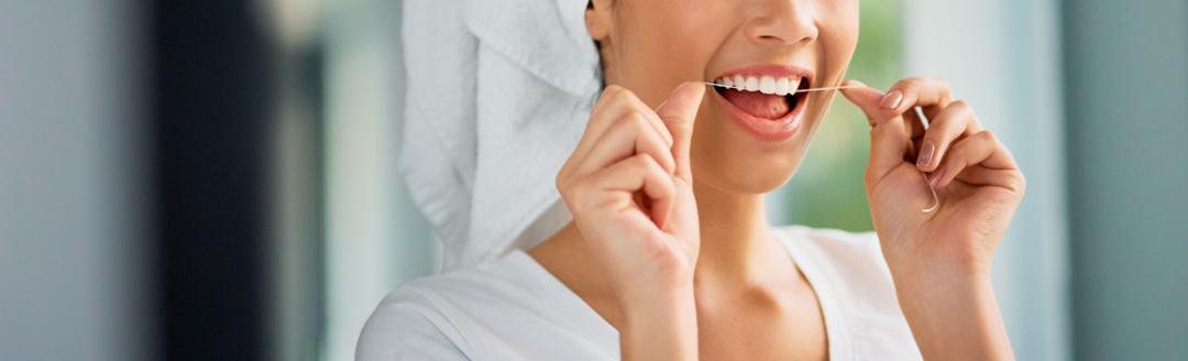 A woman is flossing her teeth using dental floss