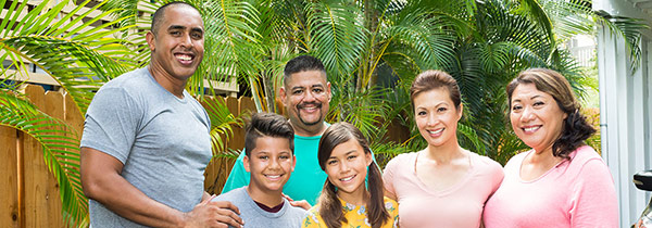 A Hawaiian family is gathered together and smiling.