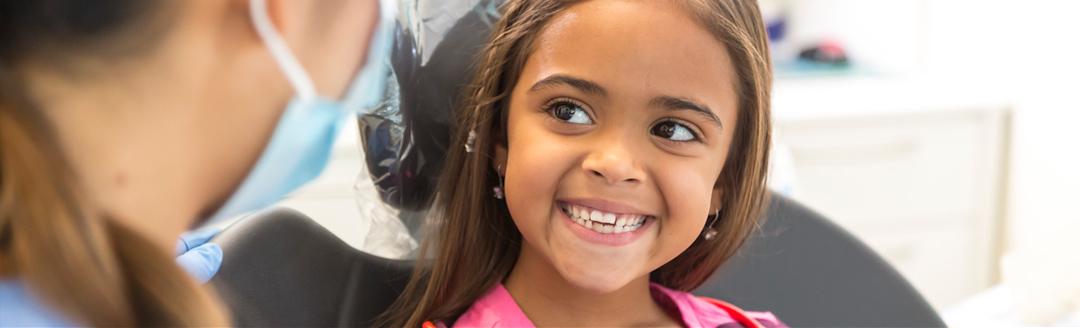 A child in the dentist's office is smiling after getting sealants for her teeth